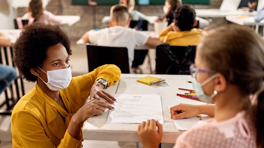 Teacher and students in classroom wearing masks.