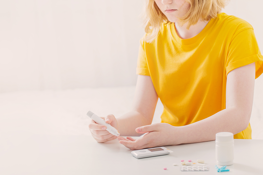 Teenager pricking finger to check glucose level.