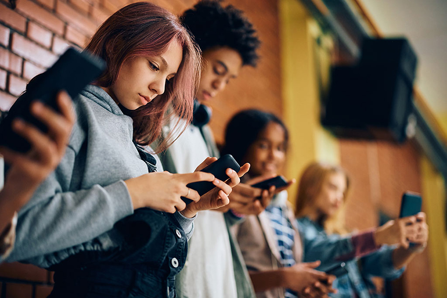 Teenagers at school on cell phones texting each other.