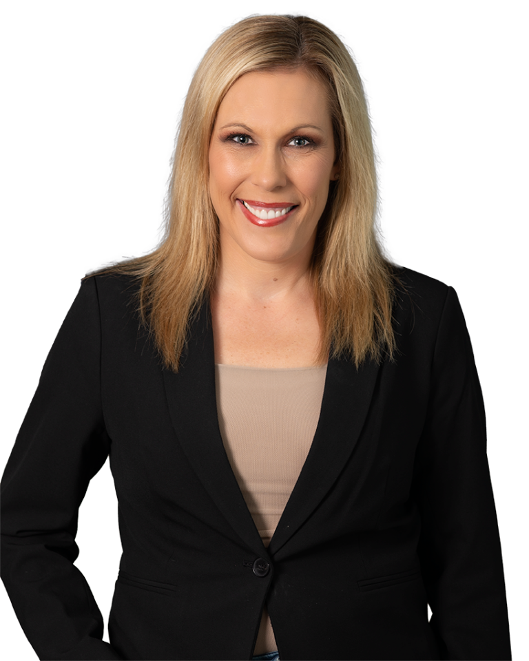 Blonde woman in a black blazer over a beige top, smiling against a dark blue patterned background.