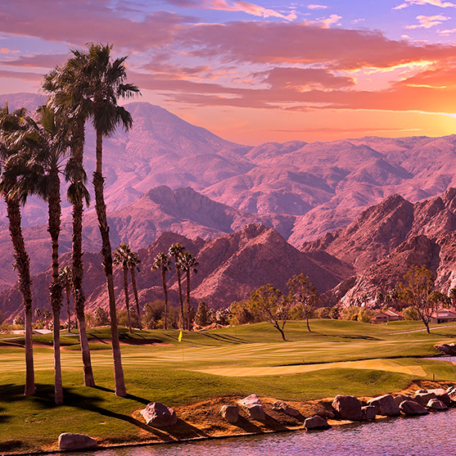 Palm trees and a golf course beside a lake, with a mountainous landscape in the background under a vibrant sunset sky, creating the perfect backdrop for a leadership conference.