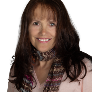 Farrell Scott, a smiling woman with long brown hair, wearing a patterned scarf and a light pink top, poses against a plain background.