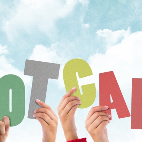 Several hands hold up large, colorful letters that spell out "BOOTCAMP" against a blue sky and clouds, highlighting the path from learning to student placement success.